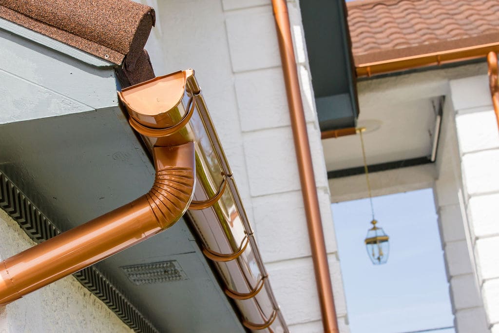 Half round guttres on a tile roof with exposed hangers Half-round gutters installed by National Gutter Pro Tampa, displaying a classic and elegant gutter design that effectively channels rainwater while complementing the architectural style of the home